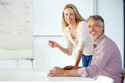 Buy stock photo Two smiling coworkers discussing business in a meeting using a flip chart and laptop - Portrait