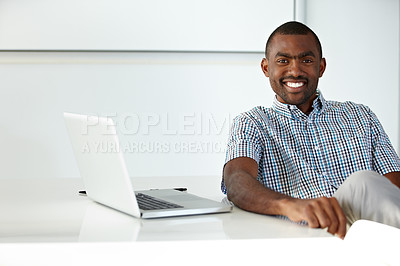 Buy stock photo A handsome ethnic businessman seated at a desk alongside a laptop