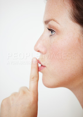 Buy stock photo Profile of a beautiful young woman with her finger on her lips