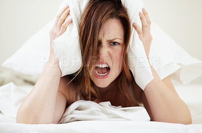 Buy stock photo Portrait, angry and woman with pillow on ears to block noise, loud sound and sleep fail on bed in home bedroom. Face, person and covering head with cushion for insomnia, tired and frustrated scream.