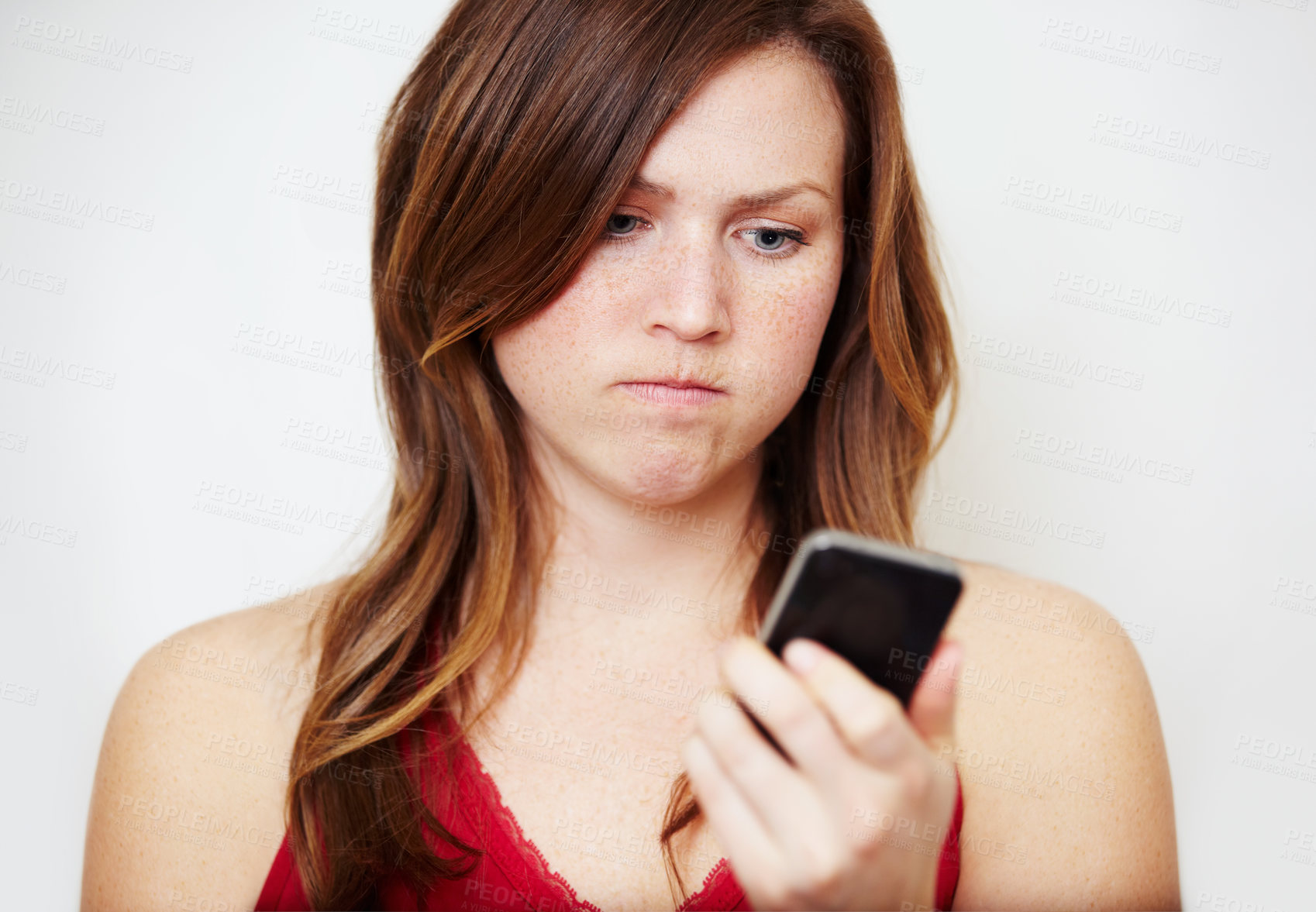 Buy stock photo Phone, text message and an angry woman in studio on a white background unhappy while reading bad news. Social media, internet and app with a young female looking upset while checking her mobile inbox