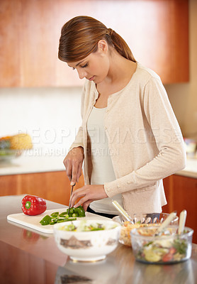 Buy stock photo An attractive young woman cooking in the kitchen