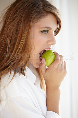 Buy stock photo A beautiful young woman biting into a delicious apple