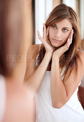 Buy stock photo A beautiful young woman applying lotion to her face