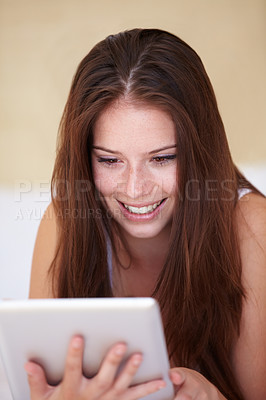 Buy stock photo Face, tablet and social media with a woman in the bedroom of her home to relax while browsing the internet. Smile, technology and app with a happy young person lying on a bed in her apartment