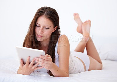 Buy stock photo Relax, tablet and app with a woman in the bedroom of her apartment for browsing on the weekend. Technology, social media or streaming with a young person lying on a bed in her home for morning rest
