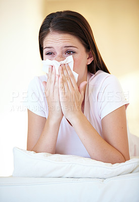 Buy stock photo A gorgeous young woman blowing her nose while lying on her bed