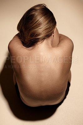 Buy stock photo Top view of a young woman embracing her kness in the studio