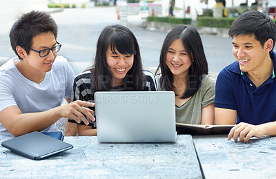 Buy stock photo Four young students sharing a laptop outside