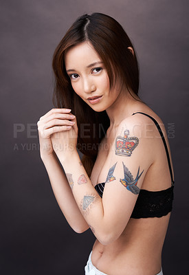 Buy stock photo Asian woman, tattoo and serious portrait in studio, dark background and show art on skin. Japanese, model and unique ink on body with lady in jeans, shorts and underwear with style and pride