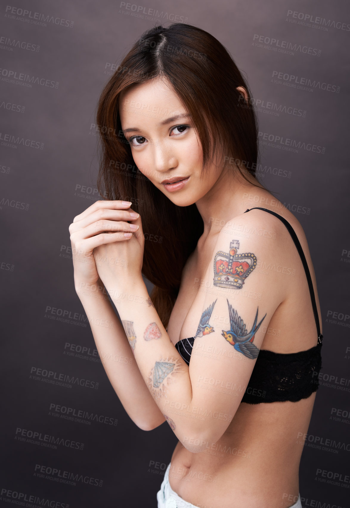 Buy stock photo Asian woman, tattoo and serious portrait in studio, dark background and show art on skin. Japanese, model and unique ink on body with lady in jeans, shorts and underwear with style and pride