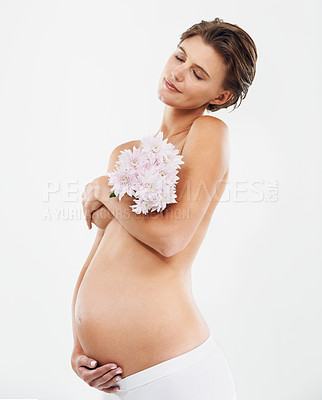 Buy stock photo Pregnancy, calm and woman with flowers in a studio holding her stomach with love, care and happiness. Feminine, maternity and pregnant female model with a floral bouquet isolated by white background.