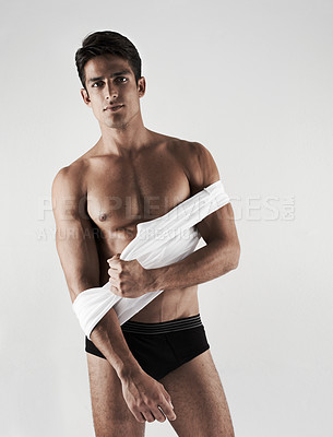 Buy stock photo Cropped shot of a handsome young man getting undressed