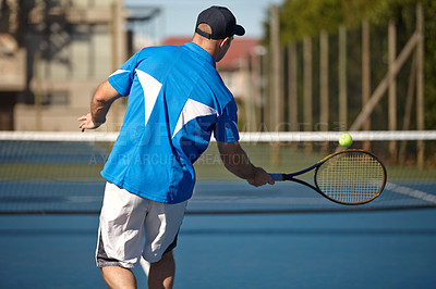 Buy stock photo Rear view of a young man about to hit a tennis ball