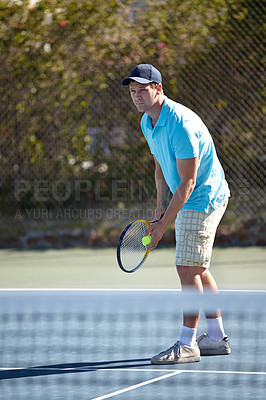 Buy stock photo A focussed young man getting ready to serve on the tennis court