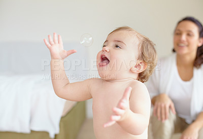 Buy stock photo Bedroom, bubble and a baby playing with his mother in their home together for love or family bonding. Kids, smile or freedom and a young infant child having fun with a parent in an apartment