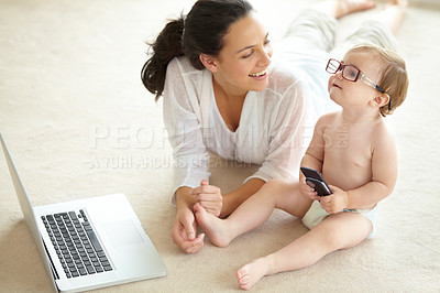 Buy stock photo A cute little baby wearing her mother's glasses and holding a cellphone while sitting in front of a laptop