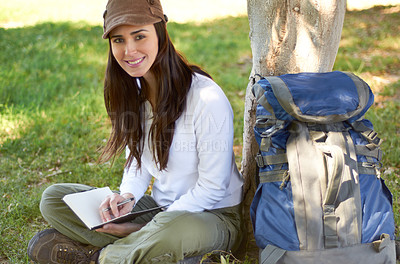 Buy stock photo A beautiful young hiker writing in her journal while camping