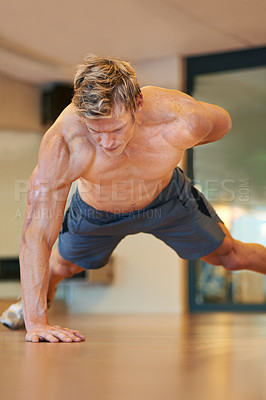 Buy stock photo Fit young man doing push ups in a health club