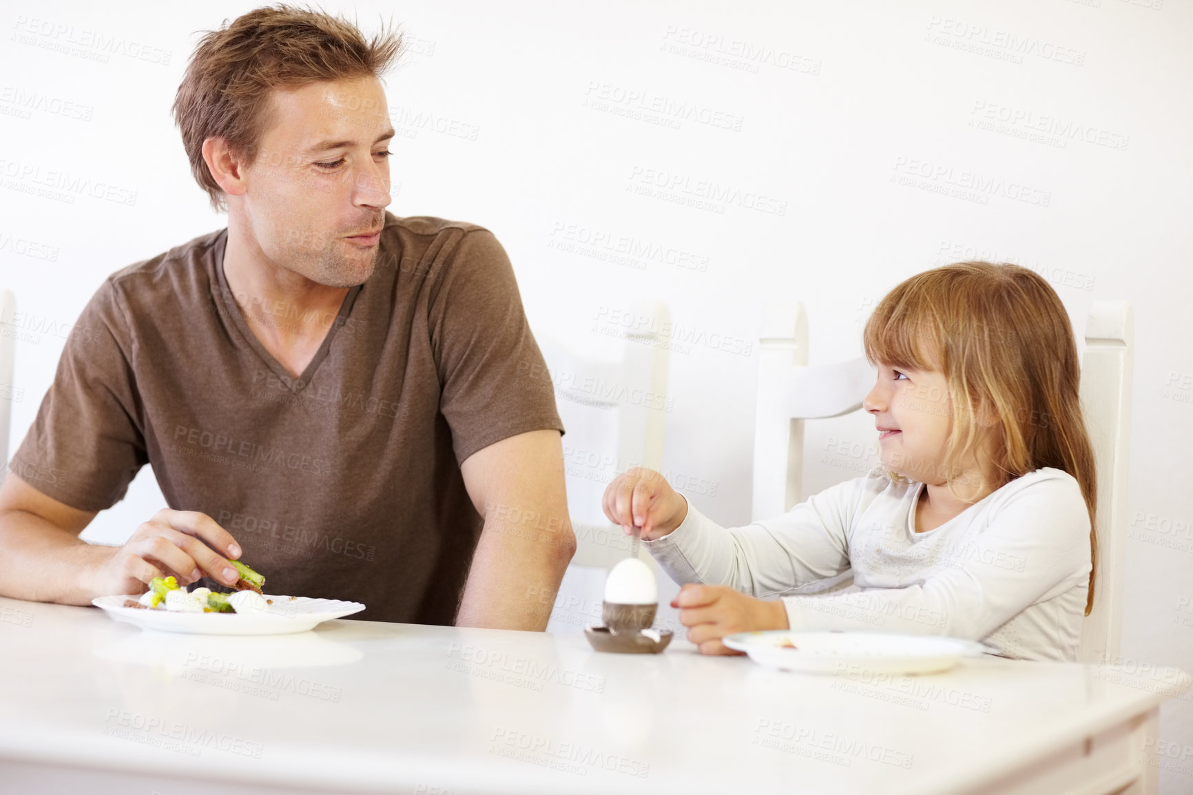 Buy stock photo Breakfast, father and daughter eating in the kitchen of their home together for morning nutrition. Food, boiled egg or meal with a man and girl child enjoying a healthy snack in their apartment