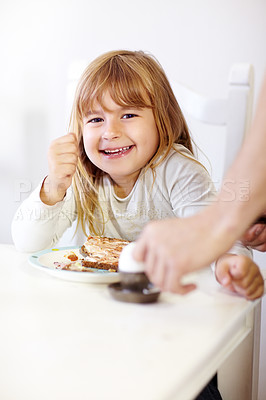 Buy stock photo A little girl smiling at the camera while eating breakfast