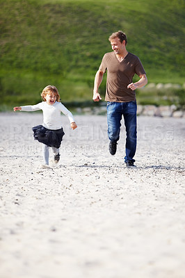 Buy stock photo A young father running on the beach with his little girl