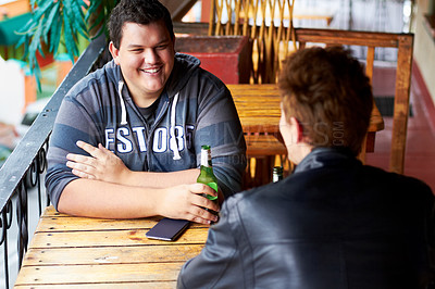 Buy stock photo Two young men sitting at a restaurant drinking beers and having a friendly discussion