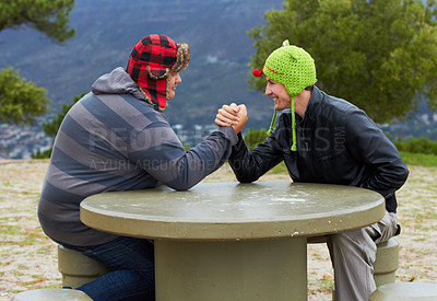 Buy stock photo Arm wrestling, happy friends and outdoor at table for sports, challenge and exercise. Strong, conflict and men holding hands for competition, power and muscle match, training or workout in park.