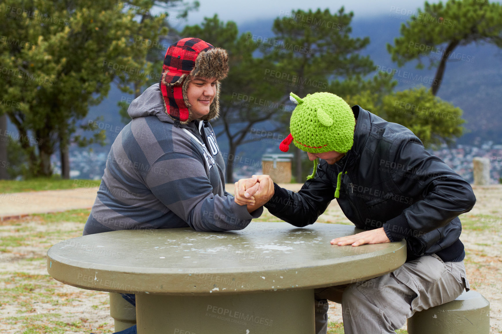 Buy stock photo Arm wrestling, friends and winning outdoor at table for sports, challenge and exercise. Strong, conflict and men holding hands for competition, power and muscle match, training or workout in park.