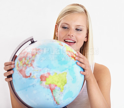 Buy stock photo A pretty young woman looking at a globe of the earth