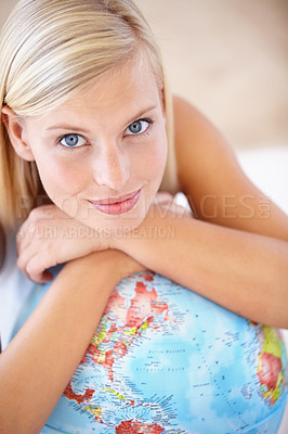 Buy stock photo A beautiful young woman resting her chin on her arms over a globe of the earth