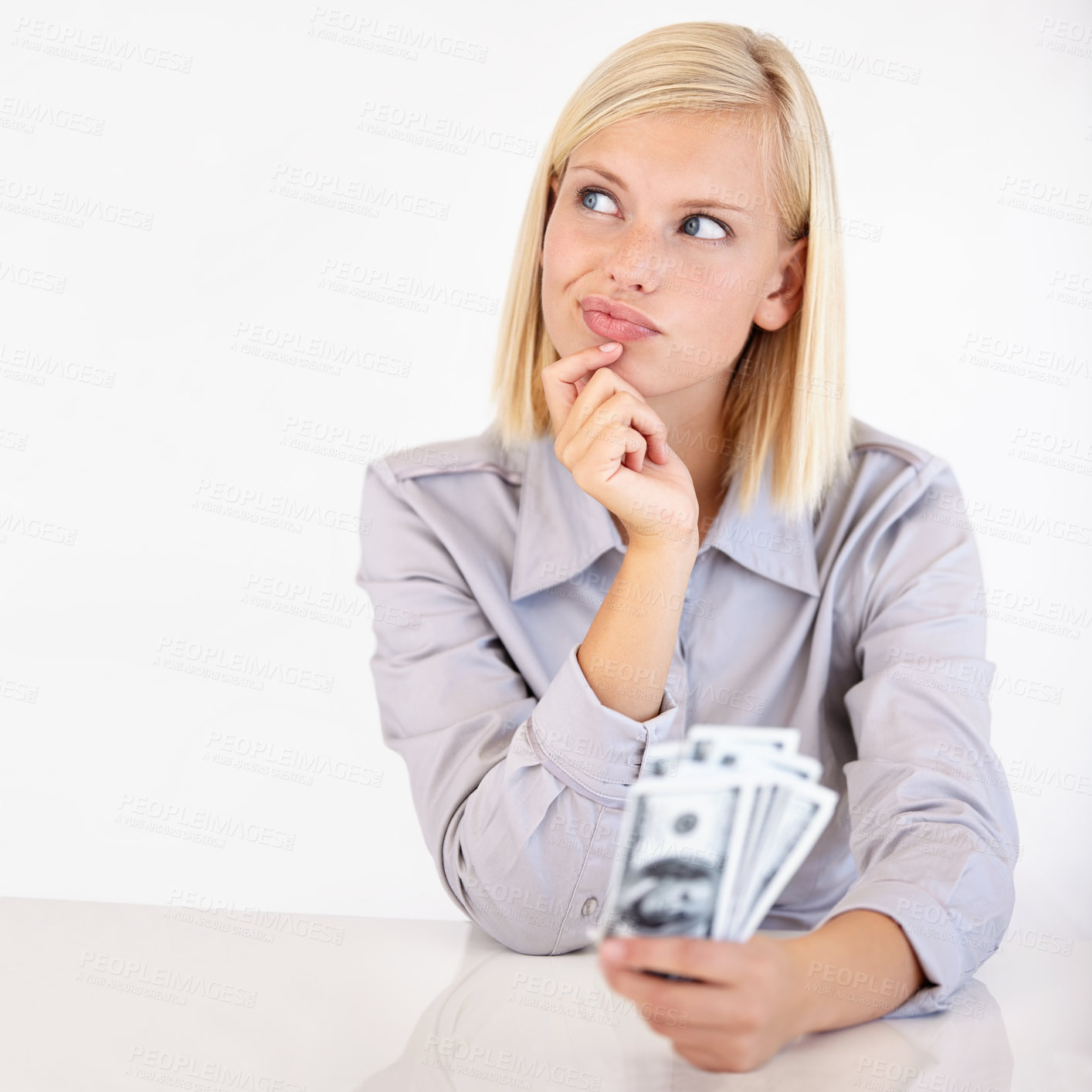 Buy stock photo A pretty young woman wondering what to do with her cash