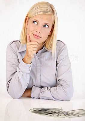 Buy stock photo A pretty young woman wondering what to do with her cash