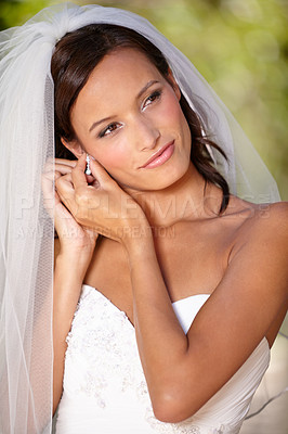 Buy stock photo Beautiful bride adjusting her earrings on her wedding day