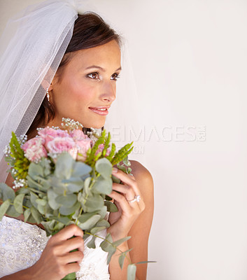 Buy stock photo Beautiful young bride looking away while holding her bouquet