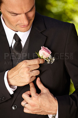 Buy stock photo Handsome young groom adjusting his boutonniere