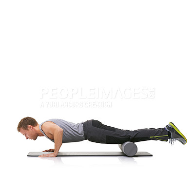 Buy stock photo A young man doing push-ups on his exercise mat with his legs raised by a foam roller