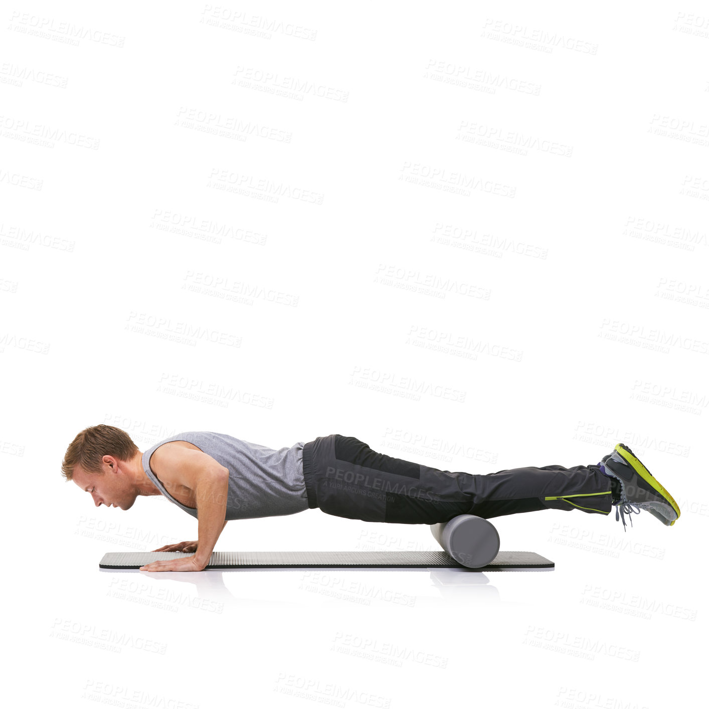 Buy stock photo A young man doing push-ups on his exercise mat with his legs raised by a foam roller