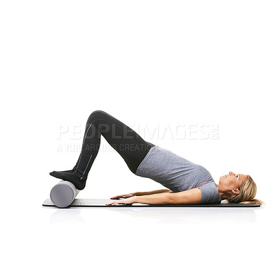 Buy stock photo A young woman lying on an exercise mat and using a foam roller to arch her back