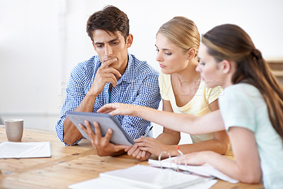 Buy stock photo Three young entrepreneurs working together on a digital tablet