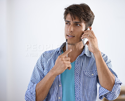 Buy stock photo Handsome young ethnic man looking sideways thoughtfully while speaking on his cellphone