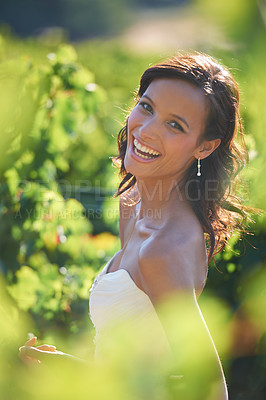 Buy stock photo A gorgeous bride smiling while standing in a vineyard