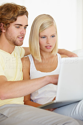 Buy stock photo A happy young couple looking at holiday destinations on their laptop