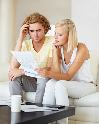 Buy stock photo A young couple reading a financial statement together in their lounge