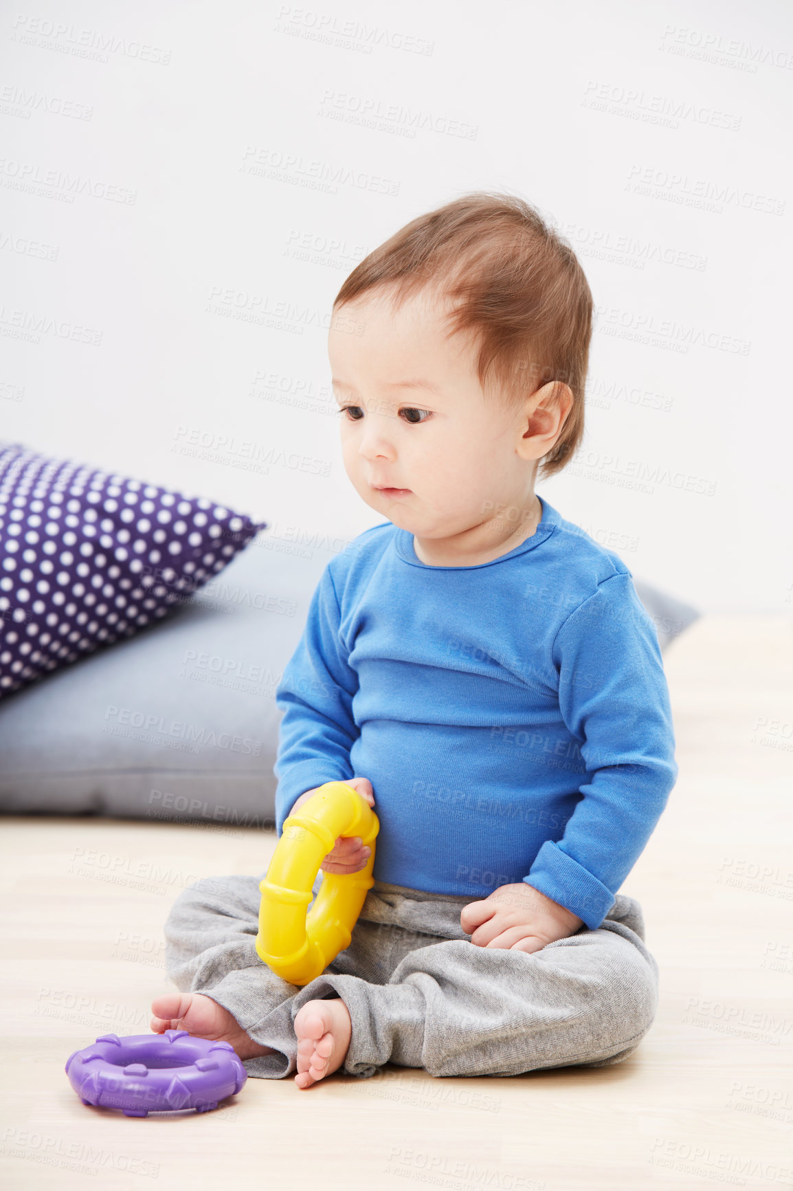 Buy stock photo Shot of a cute baby boy sitting on the floor and playing with his toys