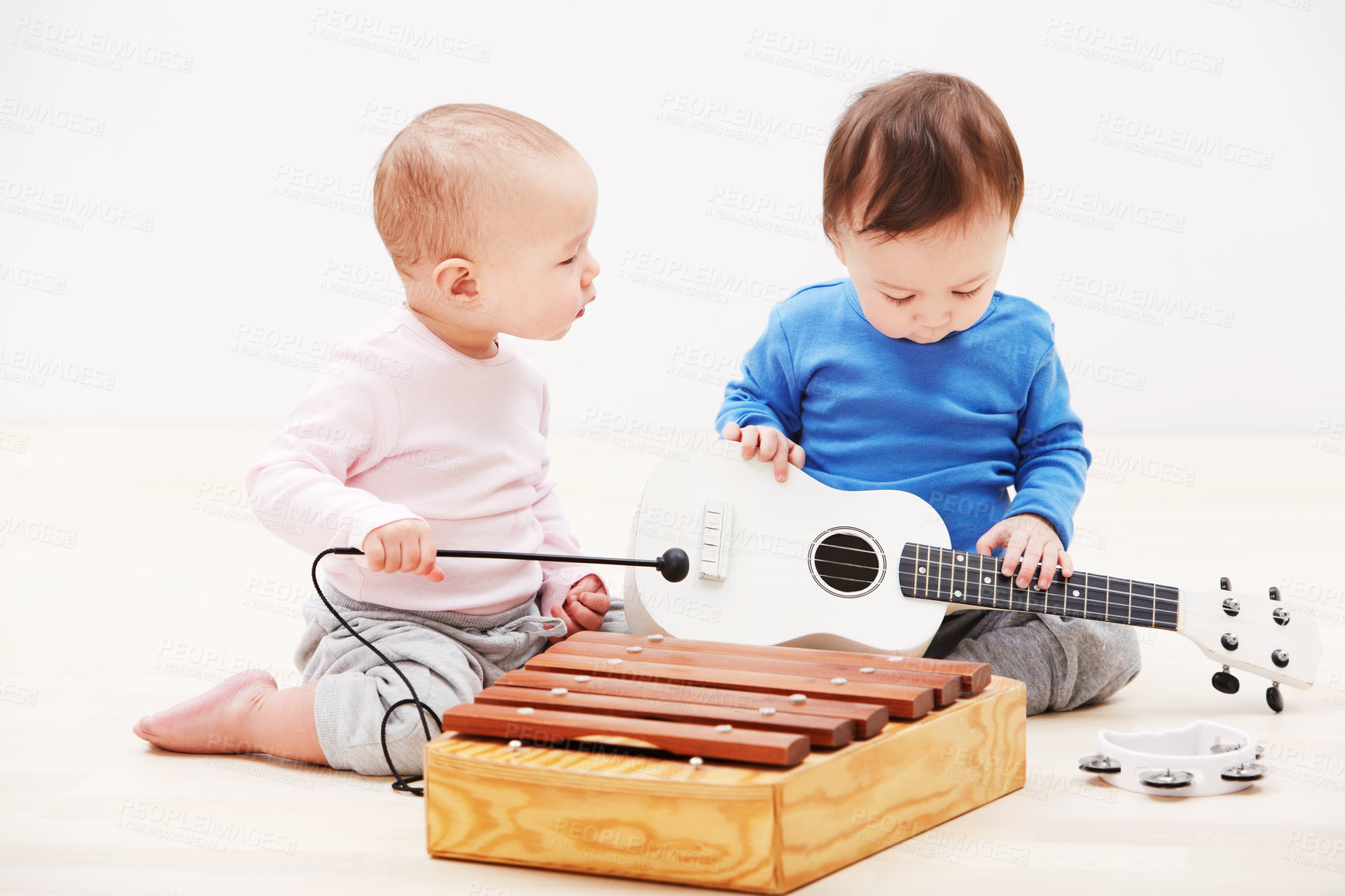 Buy stock photo Shot of two adorable babies playing with toy musical instruments