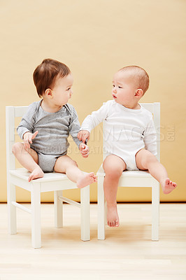 Buy stock photo Kids, chair and baby boys for growth or child development in studio on an orange background. Youth, cute or adorable and sibling or little infant children sitting together for family bonding