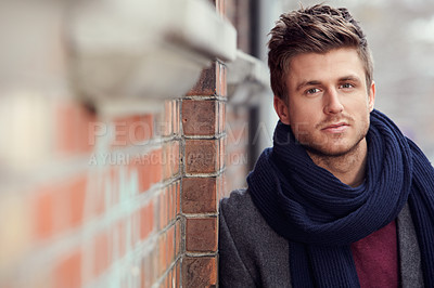 Buy stock photo Portrait, fashion and a young man in the city during winter for masculine style while leaning on a wall. Face, trendy and serious with a confident young person in an urban town to wear a warm scarf