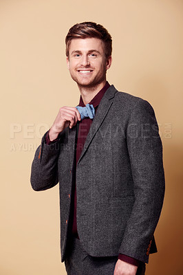 Buy stock photo Portrait, fashion and smile with a young man in studio on a tan background to wear a trendy bowtie. Happy, style and clothes with a confident model in a retro or vintage suit for a formal event