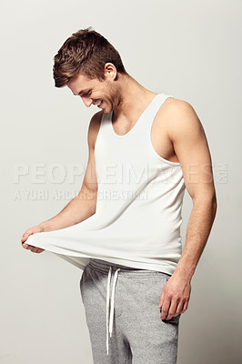 Buy stock photo Smile, morning and pajamas with a young man in studio on a white background to wake up in a good mood. Relax, happy and casual with a person looking at his vest or tank top for weekend chilling